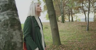 Orta atış. Ağaç dokunmadan sonbahar ormanda yürüyüş Beyaz sarışın kadın slomo. Aşağıdaki yan gimbal. Hikaye anlatımı çok genç yetişkin insanlar sonbahar forest.4k yavaş çekimde video yalnız