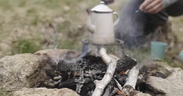 Uomo puntare tronchi di legno sul camino vicino campeggio tenda posto. mentre la donna prepara bevande calde. Coppia di persone innamorate autunno viaggio all'aria aperta nella natura. Giornata di sole d'autunno. 4k video al rallentatore — Video Stock