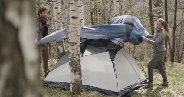 Hombre y mujer instalando una tienda de campaña en el bosque de abedules. Pareja de personas enamoradas de otoño viaje al aire libre en la naturaleza. Día soleado de otoño. 4k video en cámara lenta — Vídeos de Stock