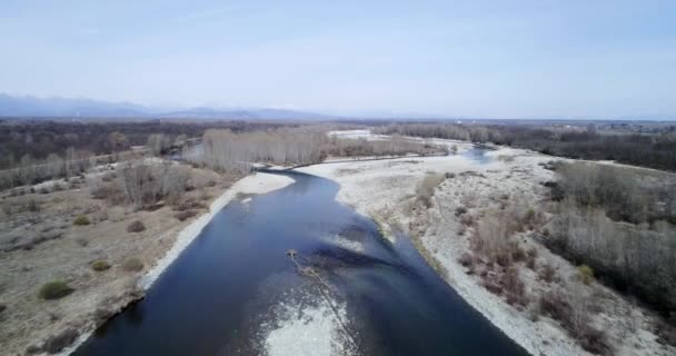 Afastando-se do leito do rio no outono ou inverno. Exterior paisagem natureza ensolarada sobre o leito do rio perto da floresta selvagem aérea estabelecer.4k voo drone estabelecendo tiro — Vídeo de Stock