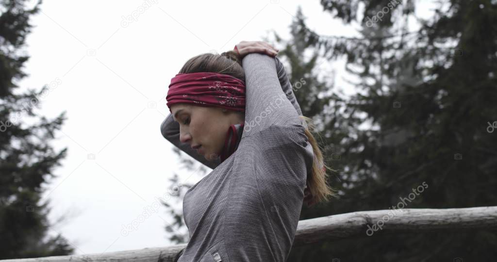 Athlete girl stretching warm up or cool down for running..Real people woman runner sport training in autumn or winter in wild mountain outdoors nature, bad foggy weather.4k 60p slow motion video