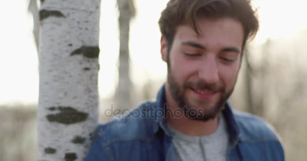 Homem sorridente relaxante ouvir música em torno de fogo lugar portrait.real amigos pessoas ao ar livre camping tenda férias no outono viagem. Queda dia ensolarado na natureza, união e amizade. 4k vídeo — Vídeo de Stock