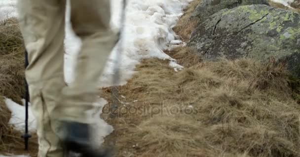 在多雪的线索路径上行走的背包徒步旅行者的男人。身后的腿细节。真正的背包客人成年后徒步旅行或在秋天或冬天在野生山户外徒步性质，多雾天气. — 图库视频影像