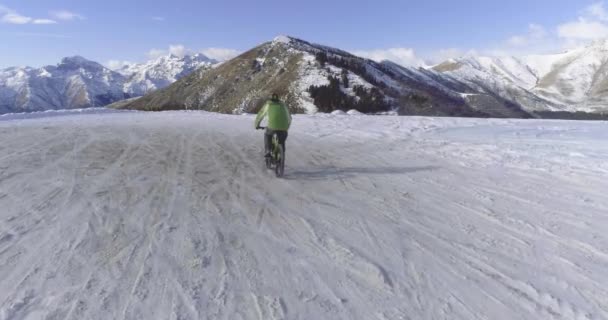 Mtb の e-自転車と冬の間に雪に覆われた道にサイクリング バイク男に前方の空中。冬の屋外の雪の上の自転車に自転車。4 k ドローン フライト ビデオ — ストック動画