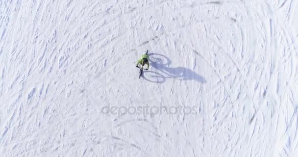 Над головой велосипедиста, катающегося на велосипеде по снежной тропе зимой на электронном велосипеде МТБ. Велосипедист на велосипеде на снегу на открытом воздухе зимой. 4k видео полета беспилотника — стоковое видео