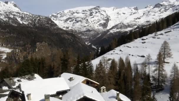 Drone aérien d'hiver s'établit sur la ville enneigée et la vallée des bois forestiers sous les montagnes glacées.Neige dans la nature de montagne à l'extérieur.Vol de côté. Voyage à la découverte des Alpes. Vidéo 4k vue du dessus — Video