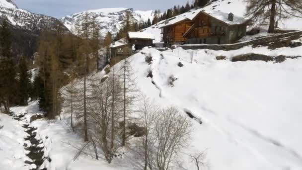 Estabelecedor de drones aéreos de inverno sobre a cidade nevada e vale de bosques florestais sob montanhas geladas.Neve na natureza da montanha ao ar livre.Voo para a frente. Viajar explorando Alpes. 4k vídeo vista superior — Vídeo de Stock