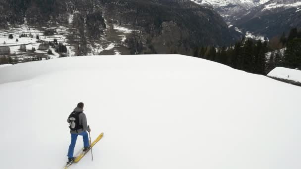 Winter-Drohnen-Etablierer über Skifahrer, die im verschneiten Waldtal unter vereisten Bergen Ski fahren. Berg Natur Schnee Outdoors.alps Ski Bergsteigen Aktivität .forward flight.4k von oben Ansicht Video — Stockvideo