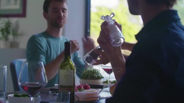 Persone che bevono, mangiano e parlano Quattro amici caucasici uomo e donna insalata mediterranea italiana, carne bistecca e pane pranzo o cena. Festa estiva a casa in casa moderna 4k video palmare — Video Stock