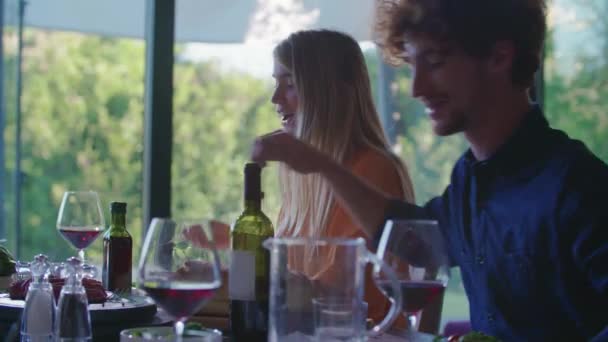 İçme, yemek ve konuşmak insanlar. Dört beyaz arkadaş erkek ve kadın Akdeniz İtalyan Salata, et et ve ekmek öğle veya akşam yemeği. Yaz Partisi evde modern ev 4k el video — Stok video