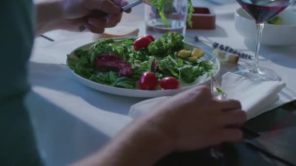 Γυναίκα τρώει λεπτομέρεια στο πιάτο. Τέσσερις φίλοι Καυκάσιος άνθρωποι Μεσογειακή Ιταλική σαλάτα, μπριζόλα κρέας και ψωμί μεσημεριανό γεύμα ή δείπνο. Καλοκαιρινό πάρτι στο σπίτι σε σύγχρονο σπίτι 4k βίντεο χειρός — Αρχείο Βίντεο