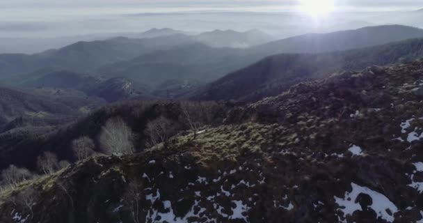 Establecimiento de vuelo aéreo de aviones no tripulados hacia adelante sobre bosques forestales con montañas y aviones en invierno. Nieve en la naturaleza de montaña al aire libre.Sun flare.Travel explorar Alpes. 4k establecimiento de vídeo — Vídeo de stock