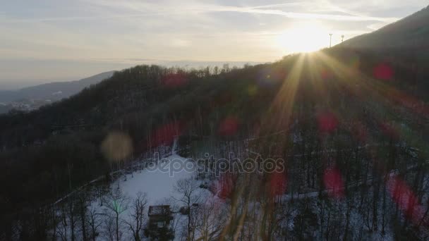 Drohnenflug über verschneiten Wäldern bei Sonnenuntergang mit Spaziergängern. Winterschnee in der Bergnatur im Freien. sunshine light.travel erkundet die Alpen. 4k Video von oben — Stockvideo