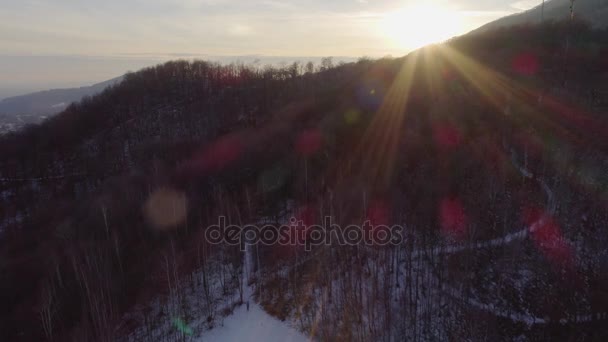 Εναέριο κηφήνα πτήση πάνω από το χιονισμένο δάσος woods στο ηλιοβασίλεμα με ανθρώπους που περπατούν. Χειμώνα χιόνι στο βουνό φύση σε εξωτερικούς χώρους. Ηλιοφάνειας light.travel Εξερεύνηση των Άλπεων. 4 k βίντεο κάτοψη — Αρχείο Βίντεο