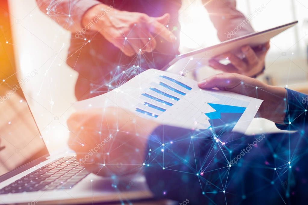 Two colleagues working on new global financial strategy plan using tablet and laptop.Modern business team innovation concept.Project meeting at office with virtual graph and chart data interface