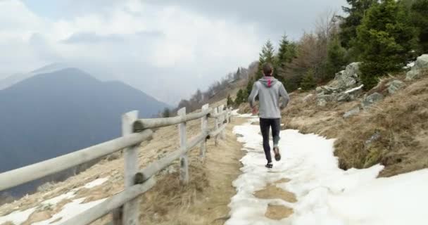 Atleta hombre corriendo a través de sendero nevado.Siguiendo behind.Real personas adulto trail runner entrenamiento deportivo en otoño o invierno en la naturaleza salvaje montaña al aire libre, mal tiempo niebla. — Vídeos de Stock