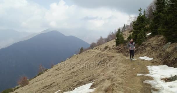 Спортсмен біжить по засніженому шляху. Слідом за фронтом. Справжні люди дорослі трейл бігун спортивні тренування восени або взимку в дикій горі на відкритому повітрі природа, погана туманна погода.4k відео — стокове відео