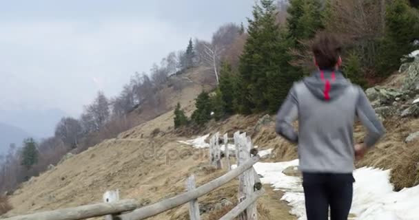 Atleet man loopt via besneeuwde pad. Volgen achter. Echte mensen volwassene trail runner sport opleiding in de herfst of winter in wilde berg buiten natuur, slechte mistige weather.4k video — Stockvideo