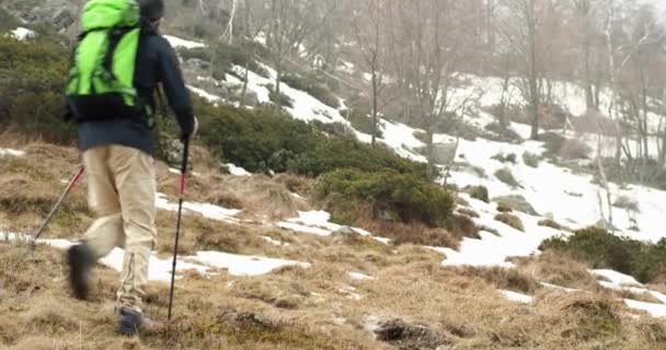 Πεζοπόρος άνδρα με σακίδιο περπάτημα στο χιονισμένο μονοπάτι. Μετά από μπροστά. Πραγματικό backpacker άτομα ενήλικα πεζοπορία ή πεζοπορία το φθινόπωρο ή το χειμώνα στην άγρια ορεινή ύπαιθρο φύση, κακό ομίχλη weather.4k βίντεο — Αρχείο Βίντεο