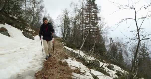 Hiker man med ryggsäck promenader på snöiga spår väg. Följande front. Äkta backpacker personer vuxna vandring eller vandring i höst eller vinter i vilda berg utomhus natur, bad dimmigt weather.4k video — Stockvideo