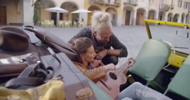 Adam gitar çalmayı kadın öğretim. Erkek kız öğrenme müzik. Yan vurdu. Çift aşk roadtrip tatil İtalyan seyahat Cabrio vintage car.4k el video