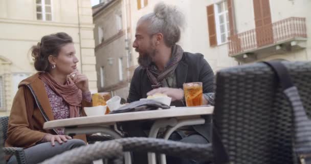 Kobieta i mężczyzna mówi o koktajl aperitif toast poza café. Średni strzał. Kaukaski para w miłości roadtrip wakacyjnych podróży włoskiej — Wideo stockowe