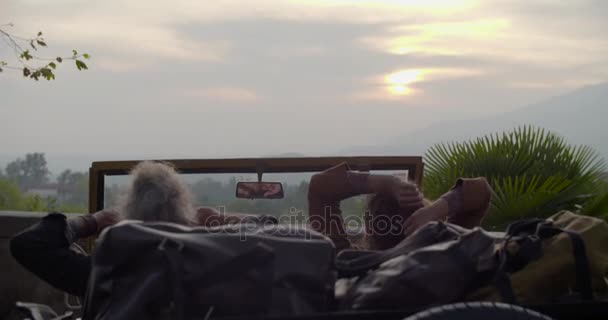 Hombre y mujer estirando los brazos relajándose y descansando en el coche mirando puesta de sol. Vista trasera. Caucásico pareja en amor roadtrip vacaciones italiano viajar en coche vintage convertible — Vídeo de stock