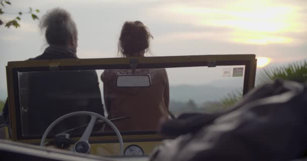 Mann und Frau umarmen sich entspannt und unterhalten sich im Auto mit Blick auf Sonnenuntergang. Kaukasisches Paar verliebt Roadtrip Urlaub Italienisch Reise auf Cabrio-Oldtimer — Stockvideo