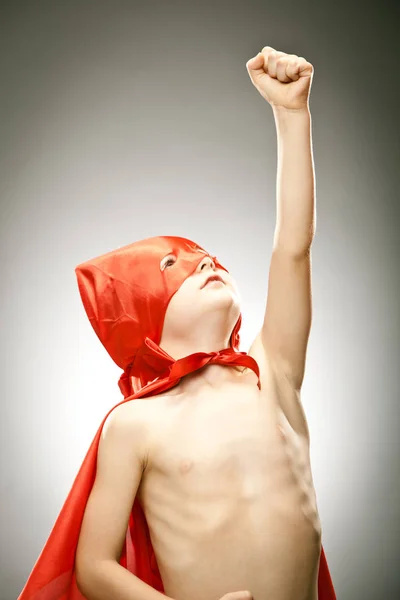 Joven niño superhéroe volar con capa y máscara retrato sobre fondo gris — Foto de Stock