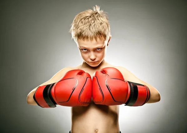 Joven niño enojado jugar boxe con guantes retrato sobre fondo gris — Foto de Stock