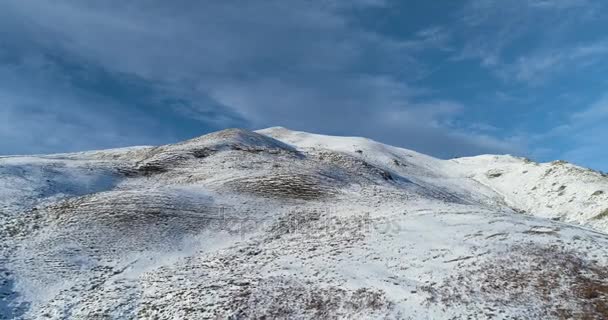 Hava Üstten bakış bulutlar ve mavi gökyüzü güneşli günde kış karlı dağ tepe üzerinde ileri. Beyaz Alp Dağları kar sezon ILDIZ. Atış kurmak peak.4k drone uçuş ulaşan — Stok video
