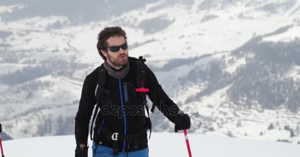 Hombre caminando ascendente a lo largo del paisaje de la cresta de nieve con la mujer friend.Mountaineering actividad de esquí. Los esquiadores deportes de invierno en la montaña alpina al aire libre.Vista frontal. cámara lenta 60p 4k video — Vídeos de Stock