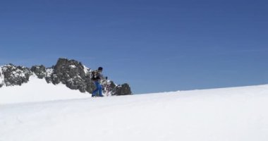 Kar ridge manzara artan yürüyen adam. Dağcılık Kayak etkinliği. Alp dağ açık insanların kış sporda kayakçı. Yan görünümü. Ağır çekim 60p 4 k video