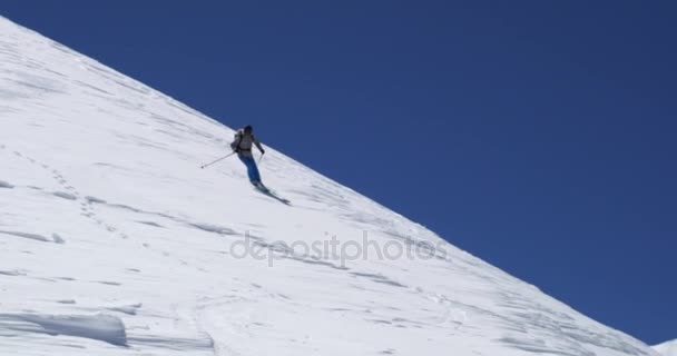 Mannen freeride skidor ner snöiga berget åsen i solig dag. Bergsbestigning ski aktivitet. Skidåkare personer vinter snö sport i alpina berg utomhus. Framifrån. Slow motion 60p 4 k-video — Stockvideo
