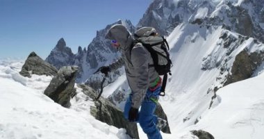 Güneşli bir günde buz baltası ile karlı Dağı üst ulaşan climber dağcı erkeği. Dağcılık Kayak etkinliği. Kayakçı insanlar kış kar spor Alp dağ açık. Yan görünümü. Ağır çekim 60p 4 k video