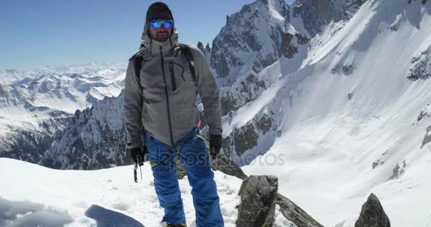 Portrait d'alpiniste sur un sommet enneigé par temps ensoleillé.Activité de ski d'alpinisme. Skier personnes sports d'hiver de neige dans la montagne alpine à l'extérieur.Vue frontale. — Video