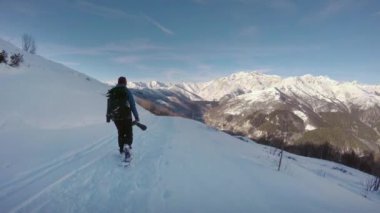 Yürüyüş ve kar ayakkabıları tarafından kışın karlı iz yolda yürüyen aşağıdaki ileri kadın fotoğrafçı. Alp kar dağ açık activity.4k video