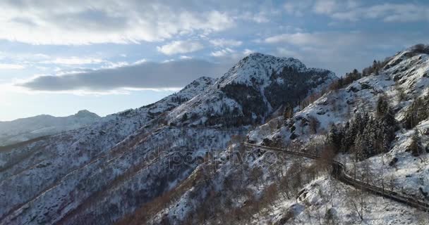 Vista superior aérea hacia adelante a lo largo de la carretera en la montaña de nieve blanca en invierno.Bosques bosques.Snowy montañas calle camino establecimiento.Sunset o amanecer sol backlit.4k drone vuelo recto hacia abajo establecer tiro — Vídeo de stock