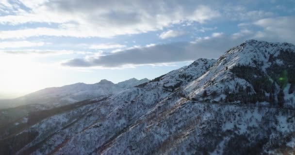 Πλευρά τροχιά εναέρια άποψη στο βουνό λευκό χιόνι το χειμώνα. Δάσος δάσος. Χιονισμένα βουνά Θεοδωρούδη δρόμου διαδρομή. Ηλιοβασίλεμα ή sunrise backlit.4k ήλιος κηφήνας πτήση ευθεία προς τα κάτω δημιουργώντας βολή — Αρχείο Βίντεο