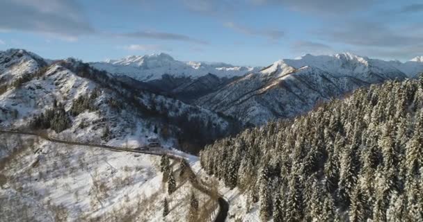 Fram övre Flygfoto på vit snö berg passerar dalen på vintern. Skogens trän. Snötäckta berg gatan sökvägen herrgårdsarkitektur. Solnedgång eller soluppgång solen backlit.4k drone flygning straight-down upprättande av skott — Stockvideo