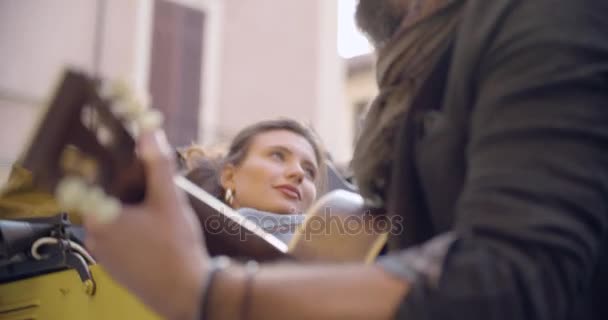 Hombre sonriendo mientras toca música de guitarra con novia.Mujer escuchando a su novio cantando canción.Pareja caucásica enamorada roadtrip vacaciones viajes italianos en coche vintage convertible.4k video de mano — Vídeos de Stock