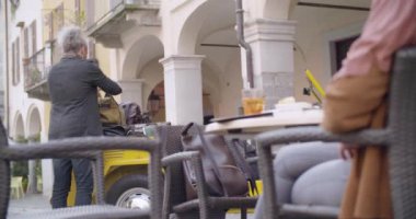 Adam Bagaj çanta almak ve kafe masaya getirmek. Orta atış. Aşk roadtrip tatil İtalyan seyahat Cabrio eski model araba üzerinde çift