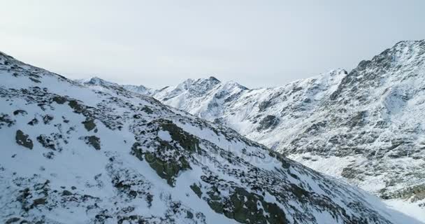 Vista superior aérea hacia adelante sobre los picos nevados de roca de montaña de invierno.Cumbres de montañas rocosas cubiertas de nieve y glaciar de hielo.Invierno salvaje paisaje naturaleza al aire libre establecimiento.4k drone vuelo estableciendo tiro — Vídeo de stock