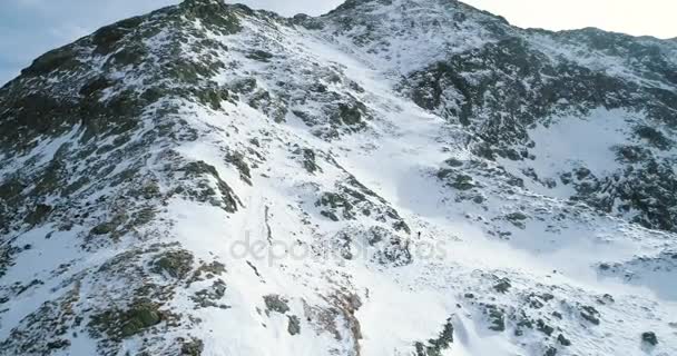Aéreo lateral sobre inverno montanha nevada com pessoas esquiador montanhismo andando até escalada.neve coberto montanhas topo e gelo glacier.Winter natureza selvagem ao ar livre estabelecer.4k voo drone — Vídeo de Stock
