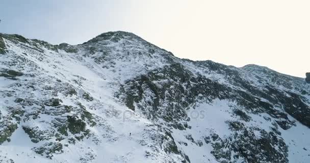 Bakåt Flygfoto över snöiga Vinterberg med bergsklättring skidåkare människor gå upp climbing.snow täckte bergen topp is glaciär. Vinter vilda naturen utomhus establisher.4k drone flyg — Stockvideo