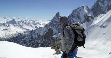 Güneşli bir günde buz baltası ile karlı Dağı üst ulaşan climber dağcı erkeği. Dağcılık Kayak etkinliği. Kayakçı insanlar kış kar spor Alp dağ açık. Yan görünümü. Ağır çekim 60p 4 k video