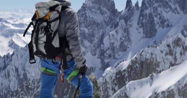 Klimmer bergbeklimmer mens bereiken van besneeuwde berg top met ijsbijl in zonnige dag. Alpinisme ski activiteit. Skiër mensen wintersneeuw sport in alpine berg buiten. Achteraanzicht. Slow motion 60p 4 k video — Stockvideo