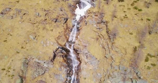 Aerial flygande framåt att vattenfall creek i gula bergen faller herrgårdsarkitektur. Utomhus snö alpina vilda naturen scape i höst eller vinter. 4 k drone flygning upprättar skott — Stockvideo