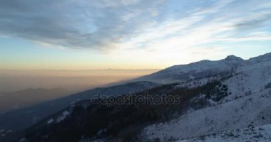 Yan hava üstten görünüm kış karlı dağ ve orman orman gündoğumu veya günbatımı üzerinde. Kar mavi saat alacakaranlık veya şafak alacakaranlık Alps dağlar sezon establisher.4k drone uçuş atış kurulması