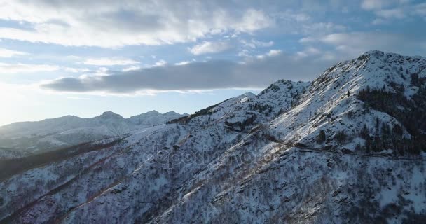 Προς τα πίσω Αεροφωτογραφία πάνω στο βουνό λευκό χιόνι το χειμώνα. Δάσος δάσος. Χιονισμένα βουνά Θεοδωρούδη δρόμου διαδρομή. Ηλιοβασίλεμα ή sunrise backlit.4k ήλιος κηφήνας πτήση ευθεία προς τα κάτω δημιουργώντας βολή — Αρχείο Βίντεο
